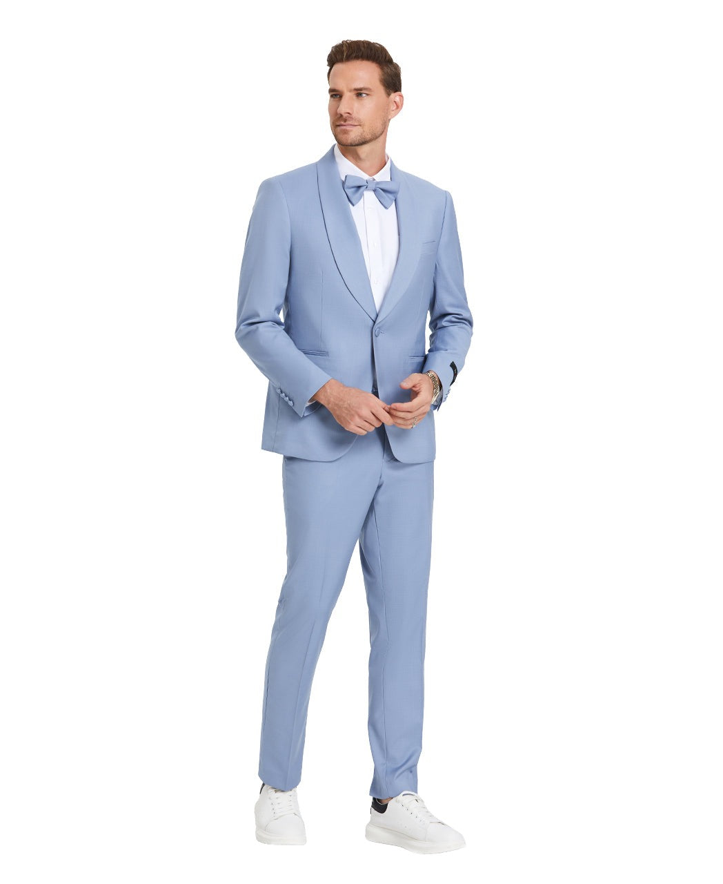 A model wearing a sky blue prom tuxedo from KCT Menswear, featuring a slim-fit design with a single-button closure and shawl lapel. The tuxedo comes with a matching bowtie for a coordinated and polished look. Perfect for proms and other formal events.