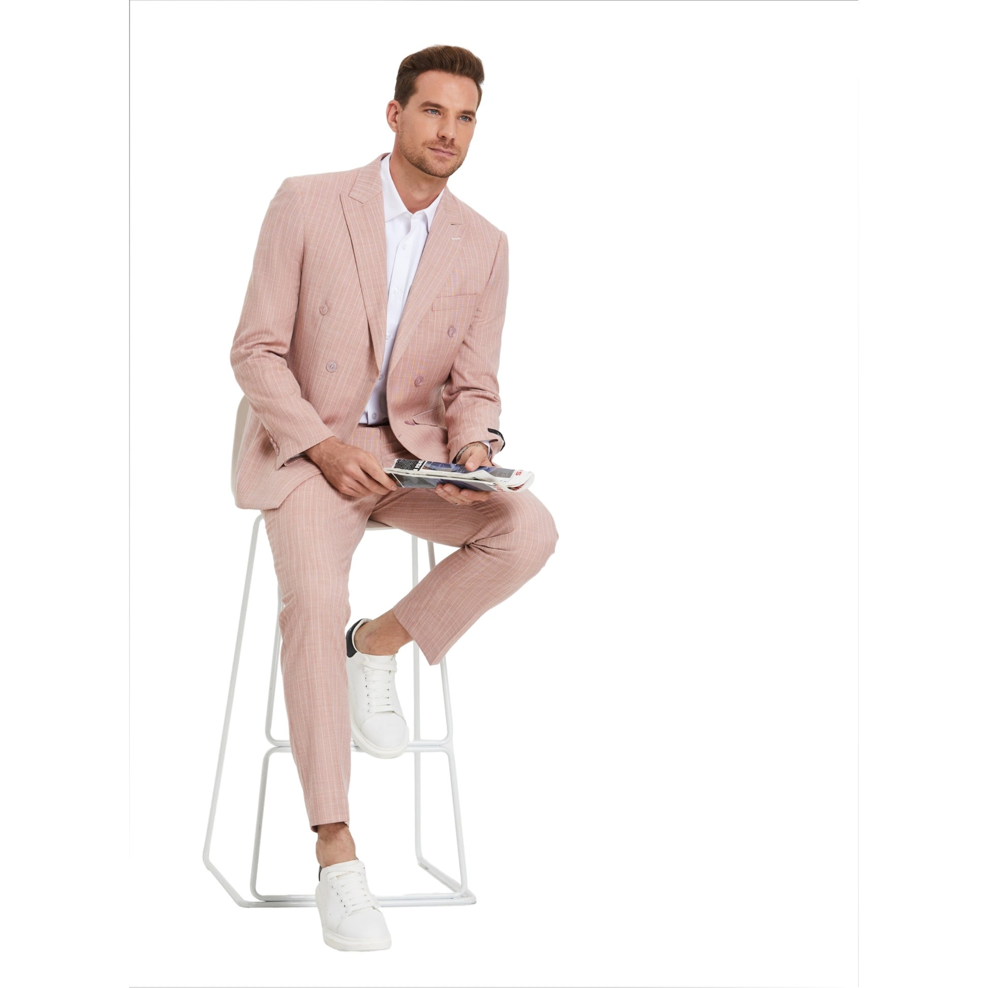 Model seated on stool wearing KCT Menswear's Pastel Pink Pinstripe Double-Breasted Suit, exuding casual sophistication