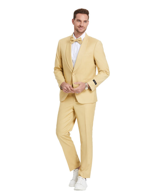 A model wearing a Light Gold prom tuxedo from KCT Menswear, featuring a slim-fit design with a single-button closure and shawl lapel. The tuxedo comes with a matching bowtie for a coordinated and polished look. Perfect for proms and other formal events