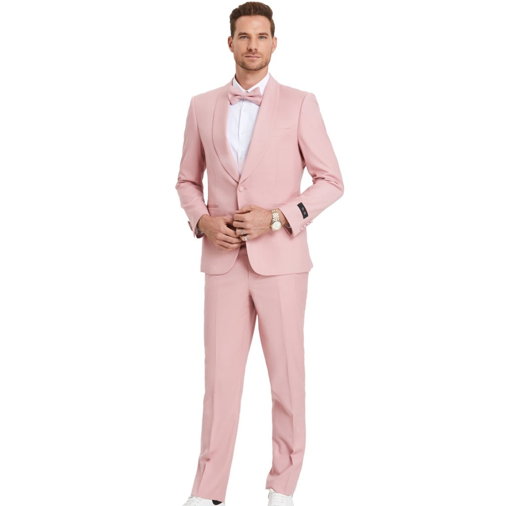 A model wearing a Light Blush  prom tuxedo from KCT Menswear, featuring a slim-fit design with a single-button closure and shawl lapel. The tuxedo comes with a matching bowtie for a coordinated and polished look. Perfect for proms and other formal events