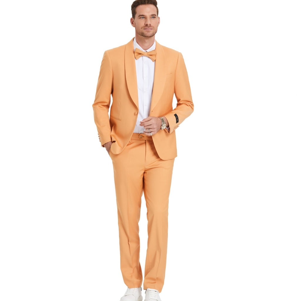 A model wearing a Light Orange prom tuxedo from KCT Menswear, featuring a slim-fit design with a single-button closure and shawl lapel. The tuxedo comes with a matching bowtie for a coordinated and polished look. Perfect for proms and other formal events