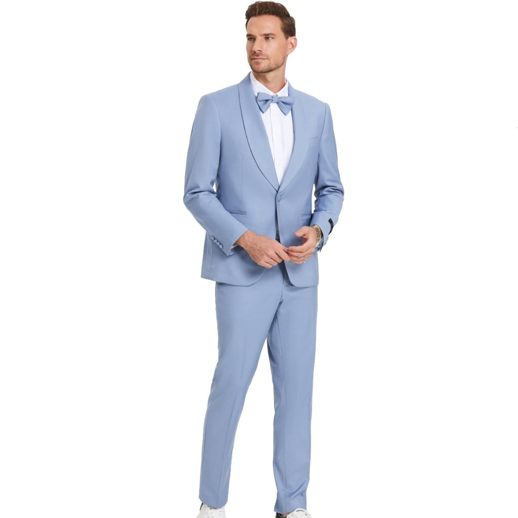 A model wearing a sky blue prom tuxedo from KCT Menswear, featuring a slim-fit design with a single-button closure and shawl lapel. The tuxedo comes with a matching bowtie for a coordinated and polished look. Perfect for proms and other formal events.